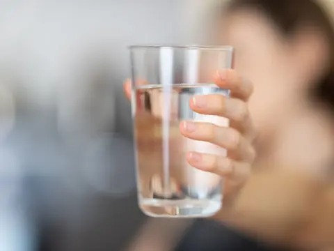 A hand holding up a clear glass of water