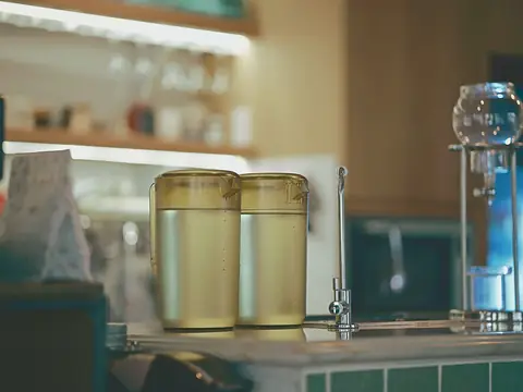 The counter of a coffee shop with brewing equipment and two jugs of water