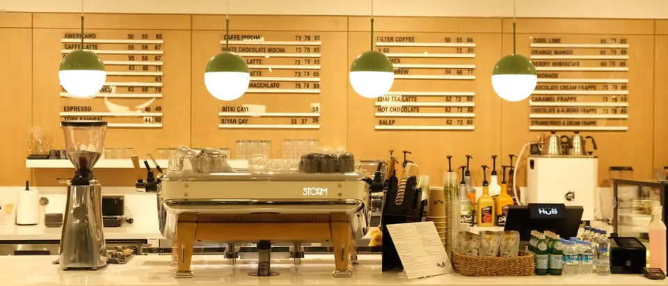 A cafe counter with an espresso machine under warm lights and menu boards