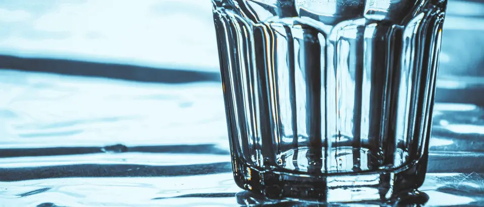 A clear glass standing in shallow rippling water