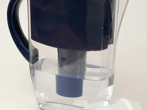 A water filter jug beside a spare replacement filter cartridge
