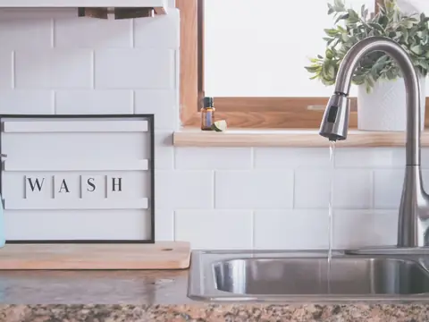 Water running from a kitchen faucet into a double sink below a window