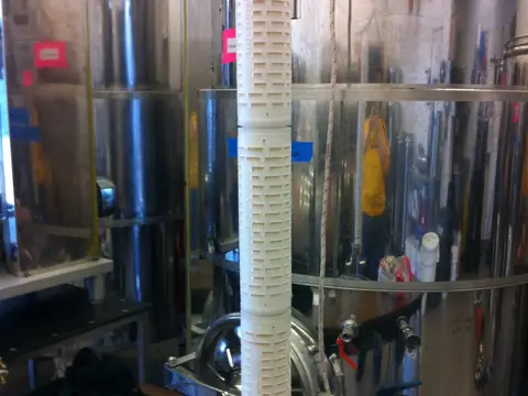 A tall pleated membrane filter cartridge standing on its base, out of its housing