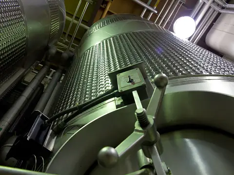 Stainless steel industrial equipment seen from below in a plant room